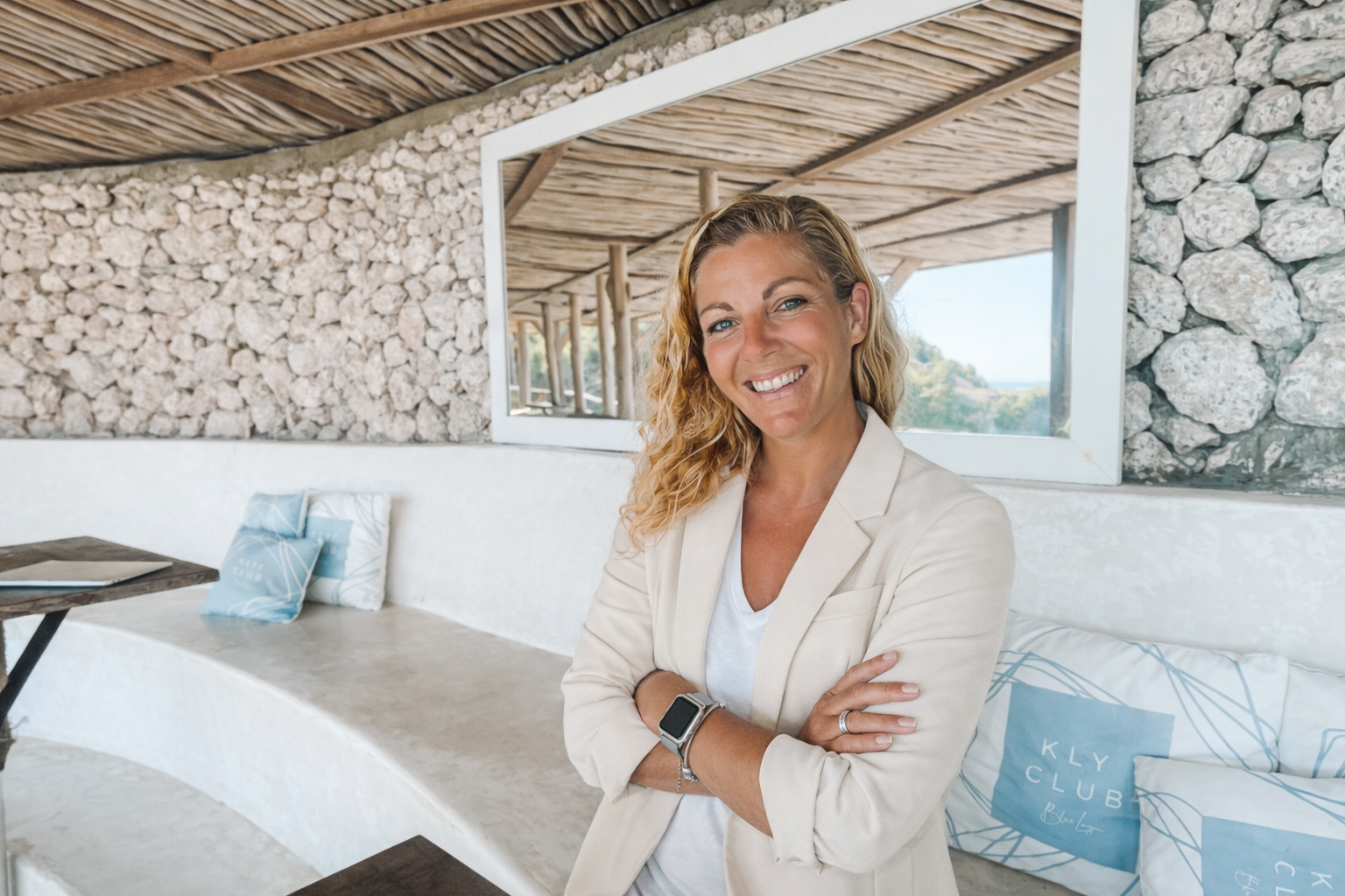 Verena Husemann smiling in a bright coastal interior, wearing a light blue top
